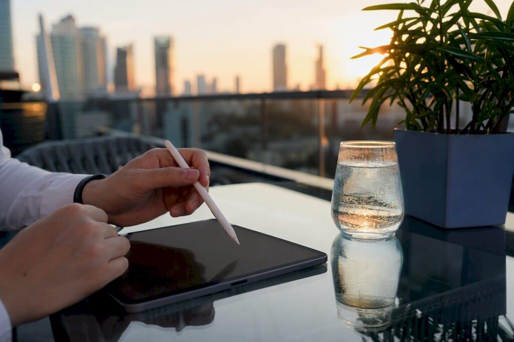 Hands hovering stylus over tablet in industrial office